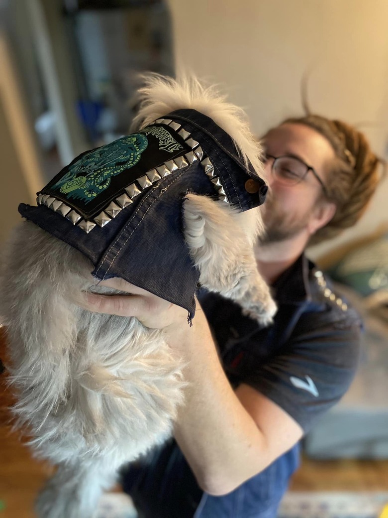 Man and cat pose together with matching denim vests.