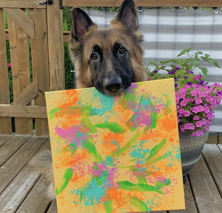 a dog showing off their painting.