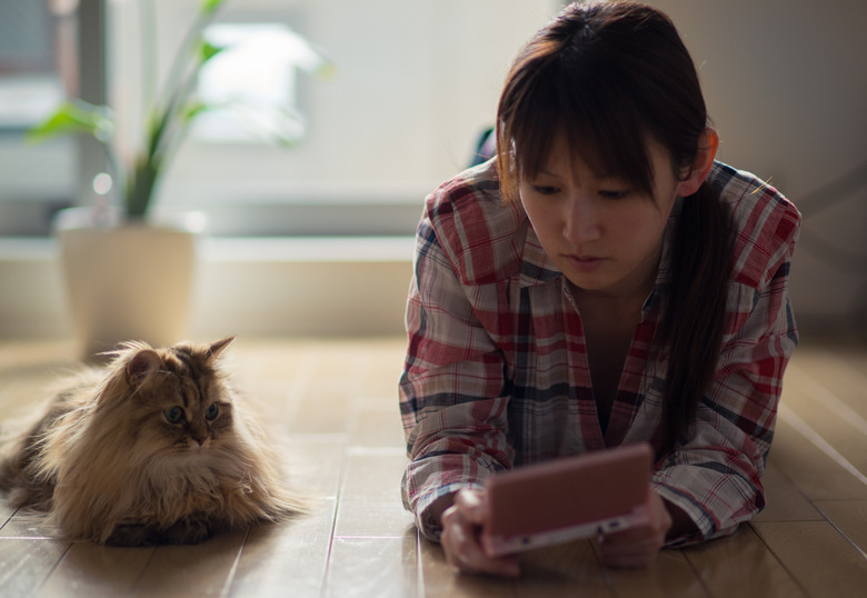 woman playing video game on the floor next to her cat
