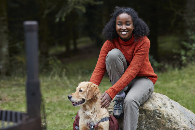 Woman sitting on rock with dog in forest