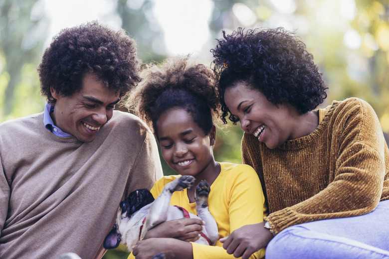 Beautiful young family lying on a picnic blanket with their dog