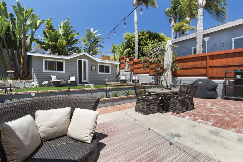 Backyard patio with seating area and grassy lounging area.