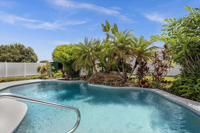 Freeform swimming pool surrounded by lush landscaping.
