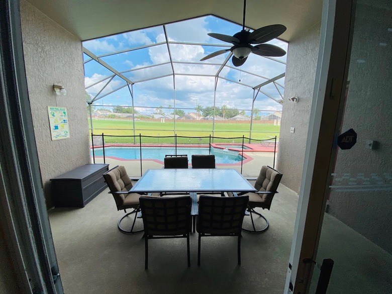 Covered patio with outdoor dining and view of enclosed pool and spa.