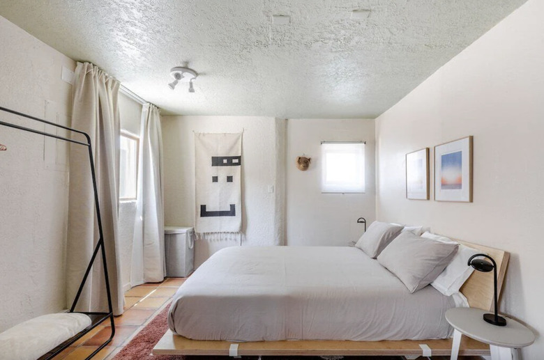 The bedroom area of the studio featuring a platform bed with gray bedding