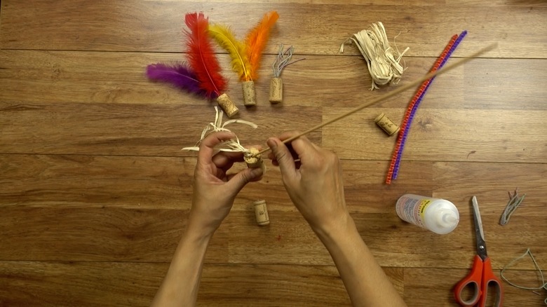Inserting raffia for DIY cat toys out of wine corks.