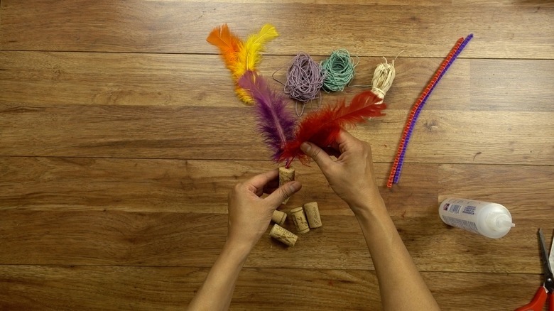 Gluing feather for DIY cat toys out of wine corks.