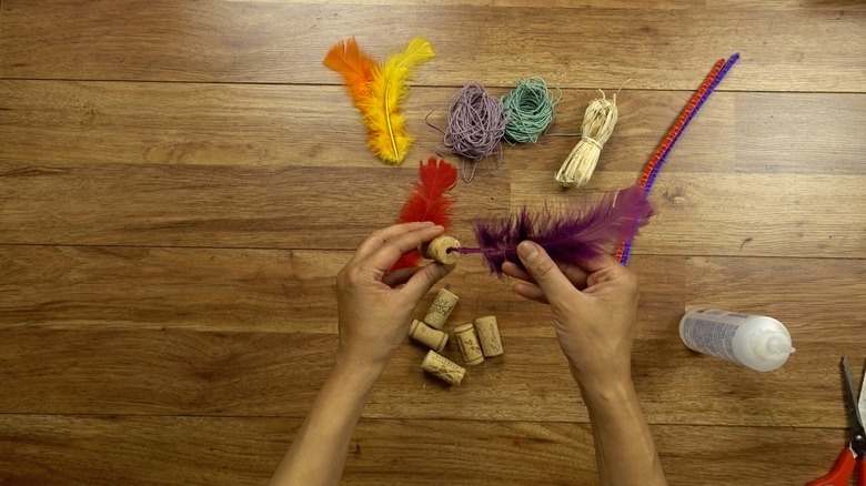 Gluing feather for DIY cat toys out of wine corks.