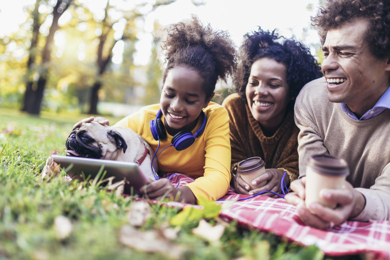 Beautiful young family lying on a picnic blanket with their dog
