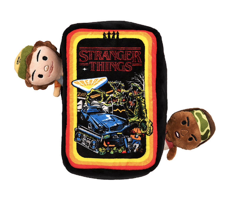 Stranger Things plush puzzle toy. Plushie Dustin and plushie Lucas are sticking out on either side of the nesting toy. The nesting toy itself says 'Stranger Things' and has images of the Palace Arcade. The back reads Stuck in the Upside Down.