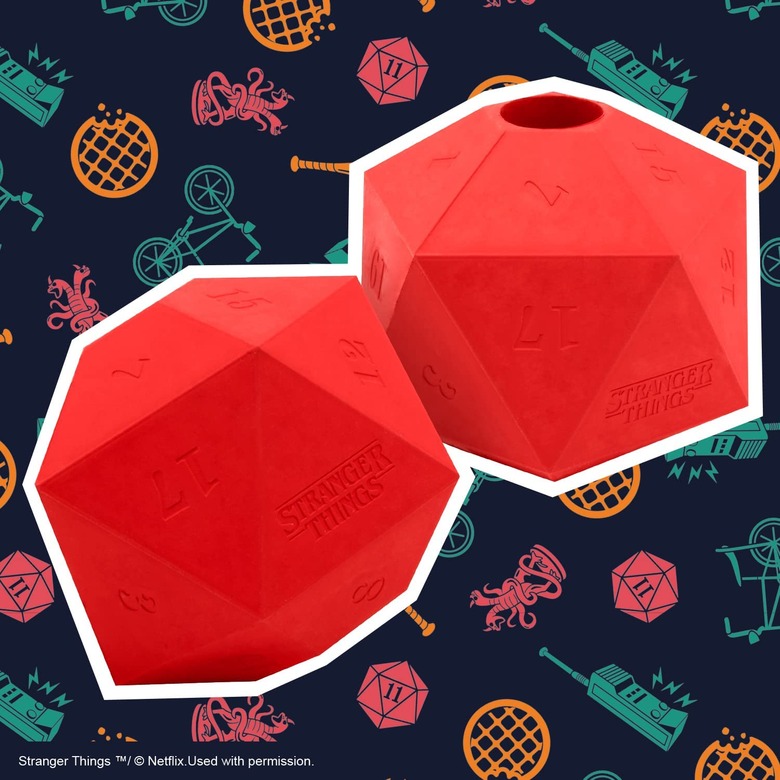 Two rubber 20-sided dice toys with a small hole at the top for inserting treats. The dice are red and have numbers and the Stranger Things logo etched into them.
