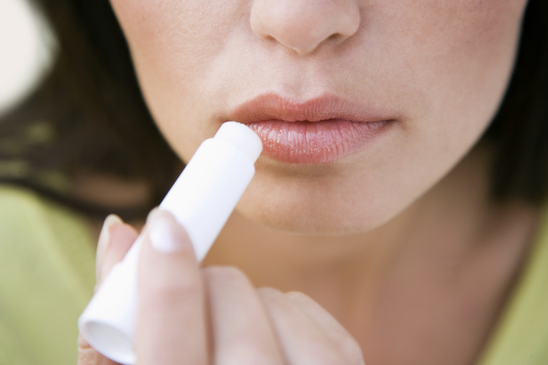 Young woman applying lip balm