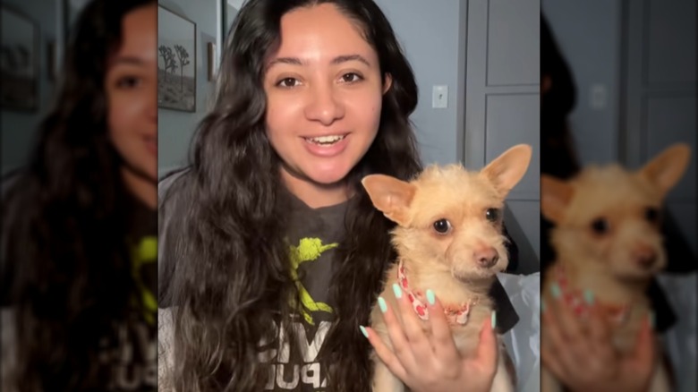 A long-haired woman holding a small dog.