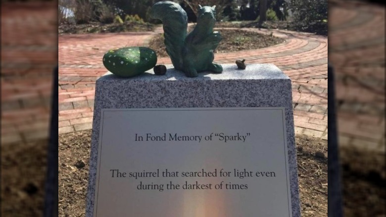 Statue of squirrel atop plinth with plaque that reads: In Fond Memory of "Sparky" - The squirrel that searched for light even during the darkest of times