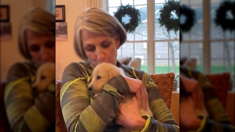 A blonde woman hugging and kissing a small blonde dachshund.
