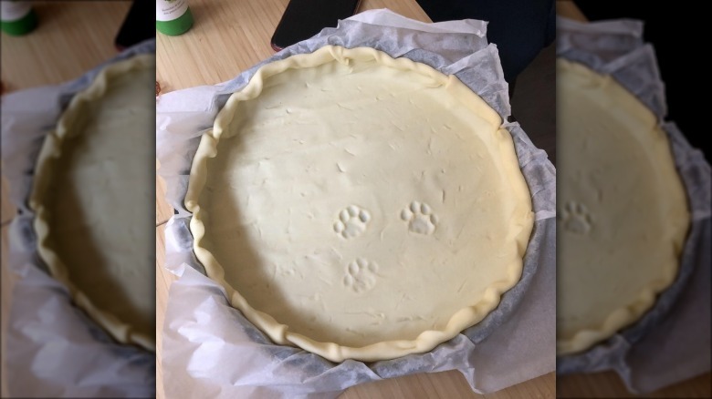 An uncooked pie crust with three cat paw prints in it.