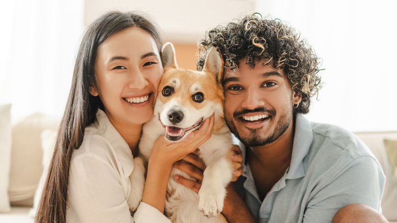 Couple snuggling their corgi