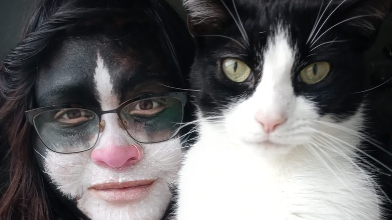 woman gets facepaint to match cat's coat