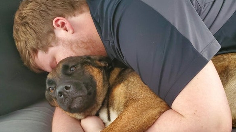 man snuggles with girlfriend's dog