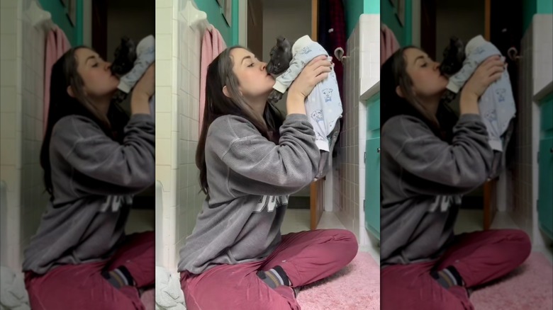 Woman kisses adorable puppy wearing pajamas