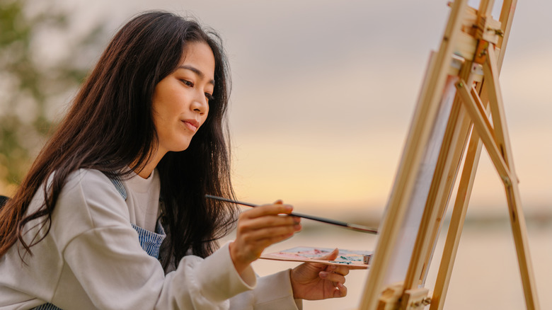Woman painting on canvas outdoors