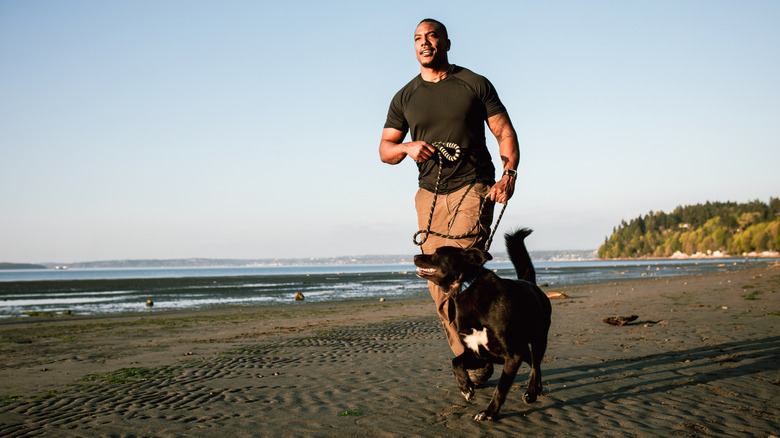 A man running with a dog on the beach.