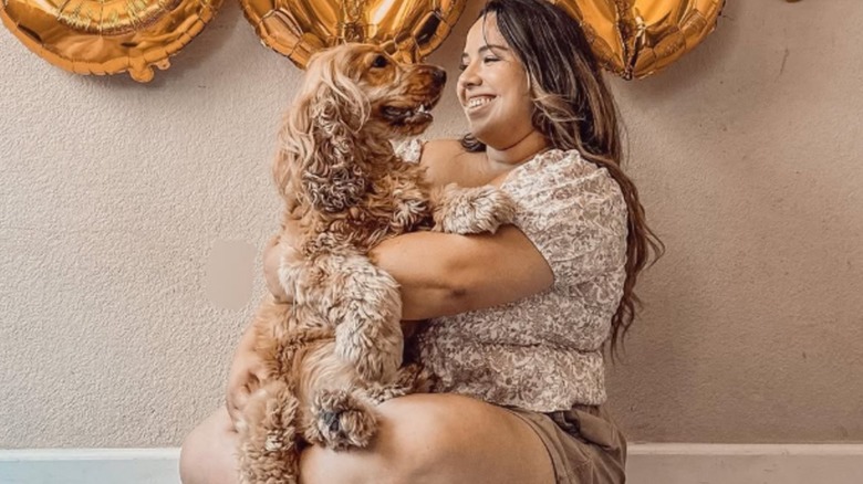 Seated woman holding her cocker spaniel, Milo