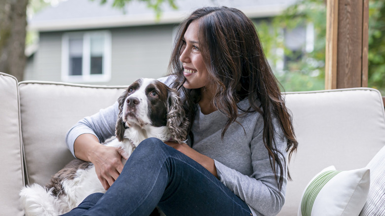 A dog and woman sit outside on a porch together.