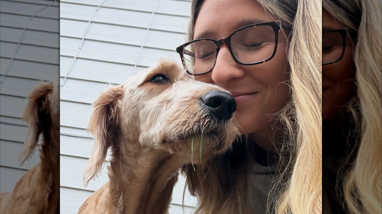 Goldendoodle leans contentedly against woman's face