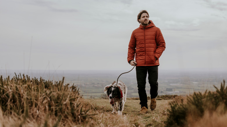White man hiking with dog through nature trail