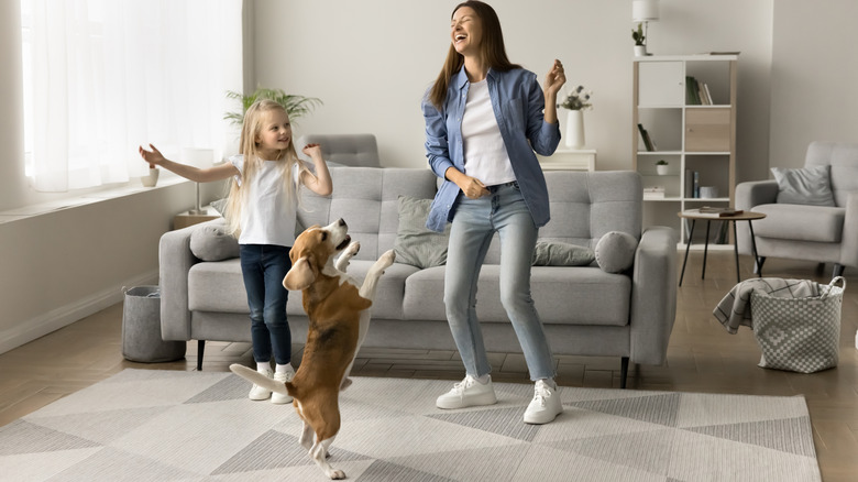 A woman and a child dancing with a beagle on its hind legs.