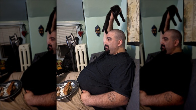 man holds cat up to keep food safe.