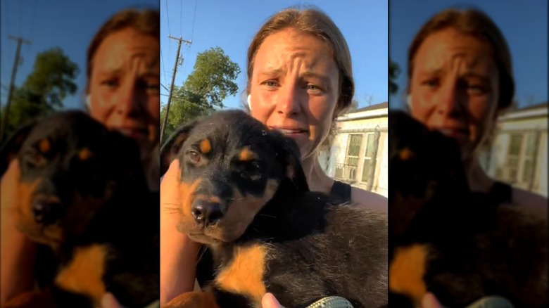 A concerned looking woman holding a Rottweiler puppy.