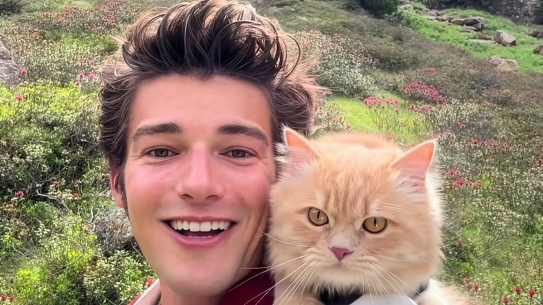 Smiling man with ginger cat on his shoulder
