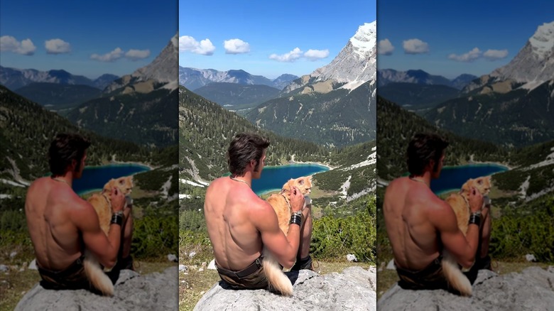Shirtless man with ginger cat on his lap, gazing at the lake and mountains