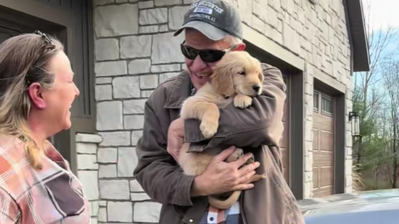 Man cuddling golden retriever puppy