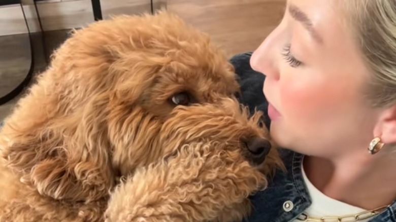 Goldendoodle and white woman look into each other's eyes while the dog lays on the woman's chest.