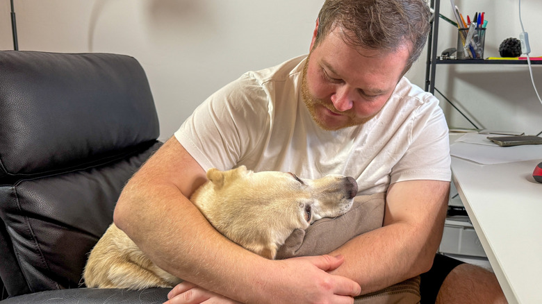 A man hugs a dog.