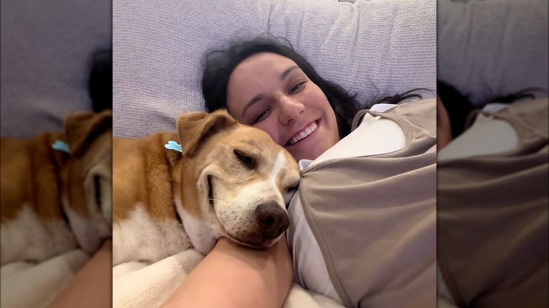 Woman and smiling dog cuddle on the couch