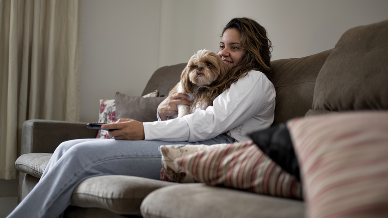 Woman cuddling her shih tzu on a couch