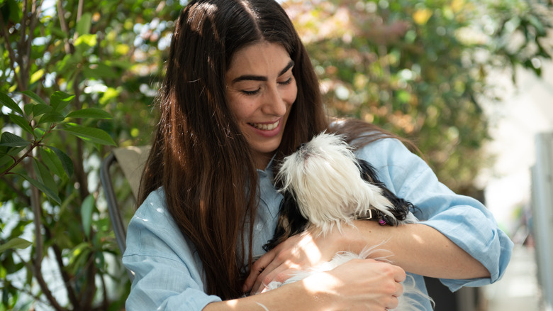 Happy woman cuddling a black and white dog.