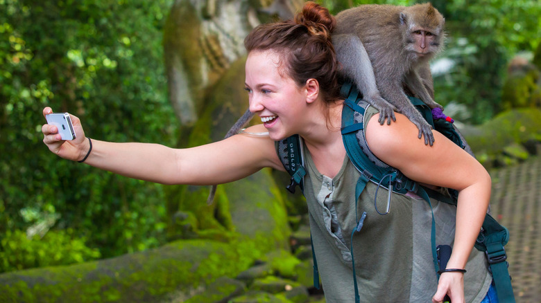 Person posing for a selfie with a monkey on their back.