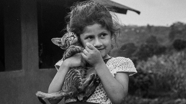 Kid hugging a fussy kitten.