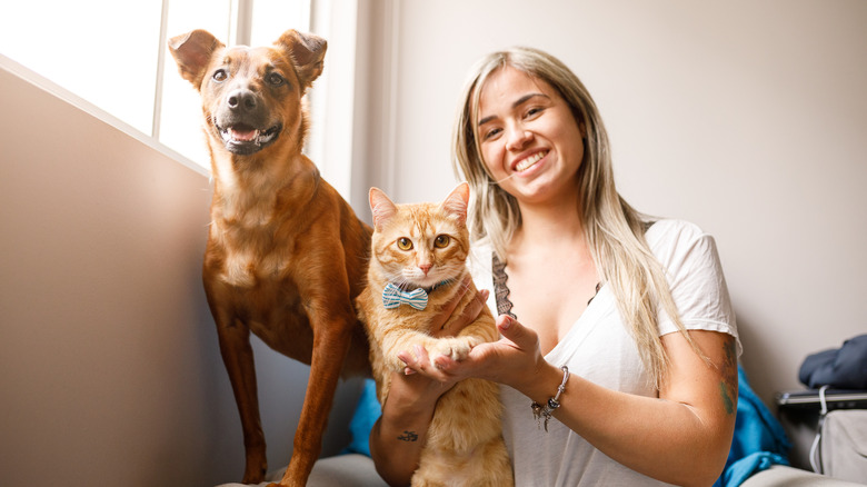 A young woman poses with a cat and a dog