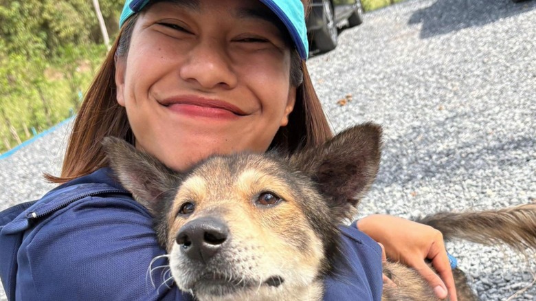 Woman with Happy Doggo smiles while hugging a senior mixed dog.