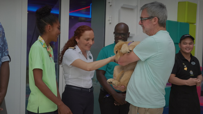 Group of people smiling as they pet Sailor the golden retriever on board the Star of the Seas