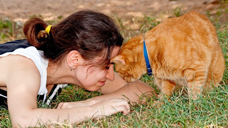 Woman happily butting heads with a ginger cat