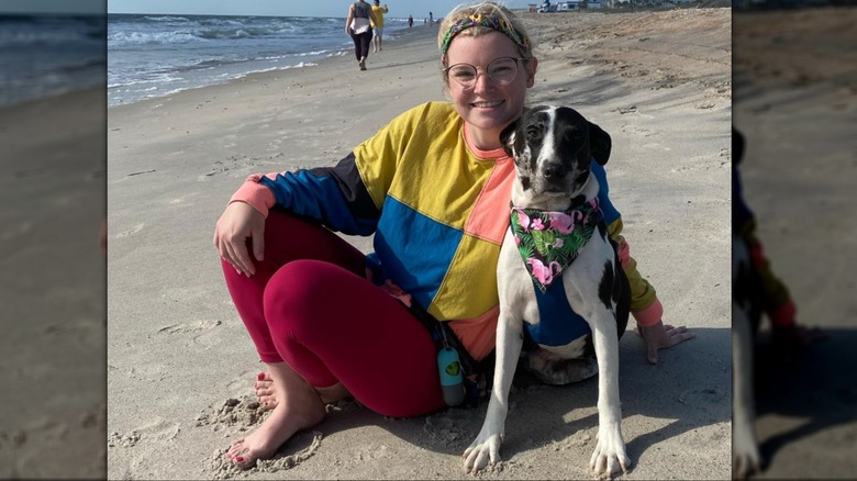 Woman seated on sand at beach with dog