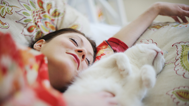 Sleeping woman and sleeping cat sharing a pillow
